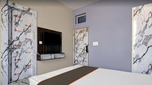 Une chambre d’hôtel avec un grand lit, une fenêtre et une porte ornée d’un motif en marbre.