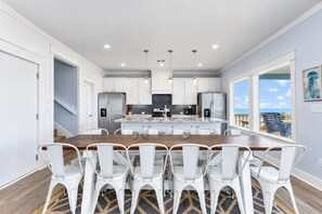 A modern kitchen with a central island, white cabinetry, stainless steel appliances, and a view to the outside.