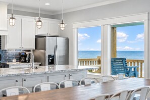 A kitchen with a large island, stainless steel appliances, and a view of the ocean.