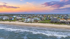 A coastal residential area with beachfront properties, a sandy beach, and a view of the ocean.