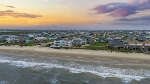 A coastal residential area with beachfront properties, including houses with balconies and a beach in the foreground.
