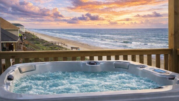 Ein Whirlpool mit Blick auf Strand und Meer bei Sonnenuntergang.