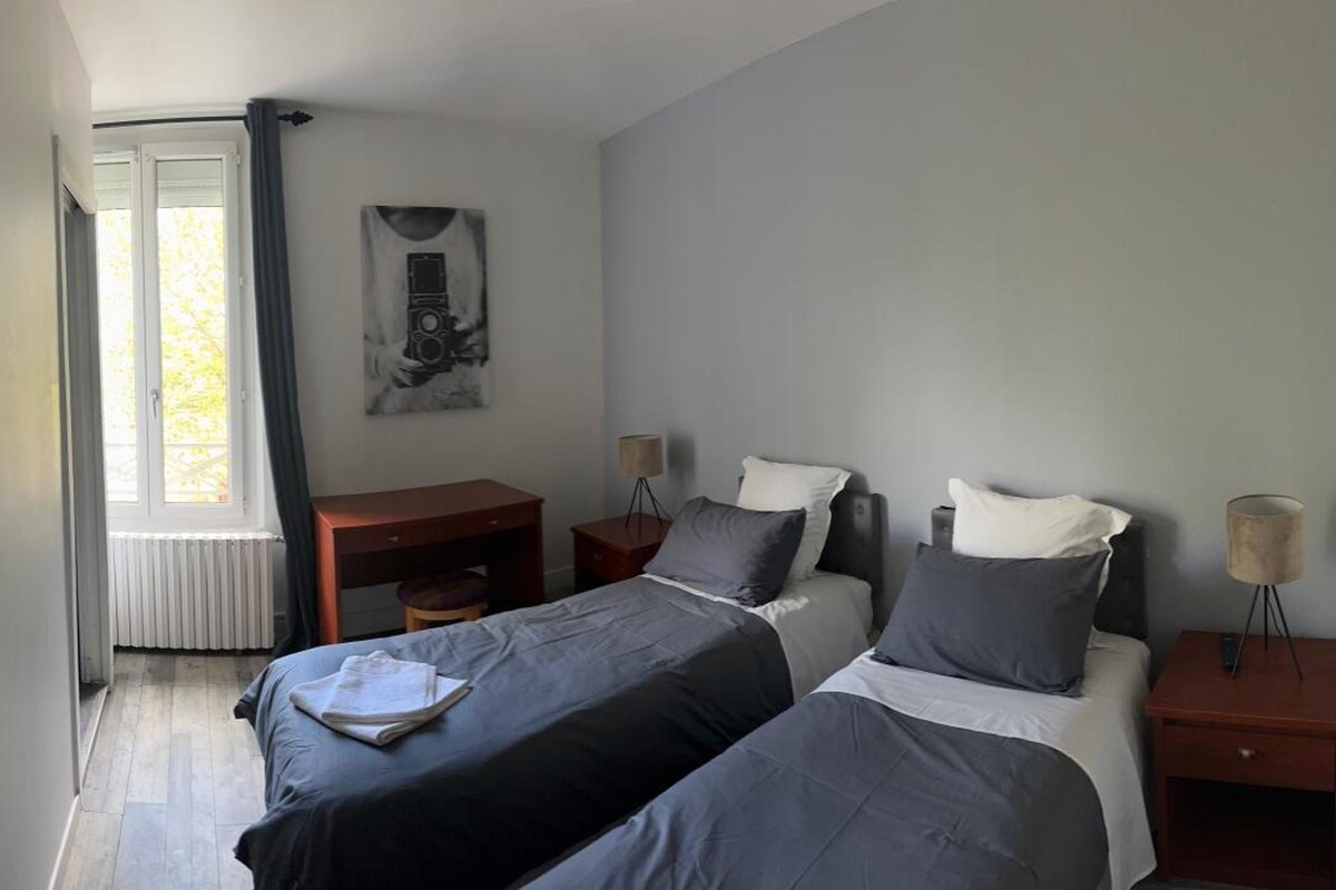 Een slaapkamer met twee bedden, een bureau, een stoel en een lamp.