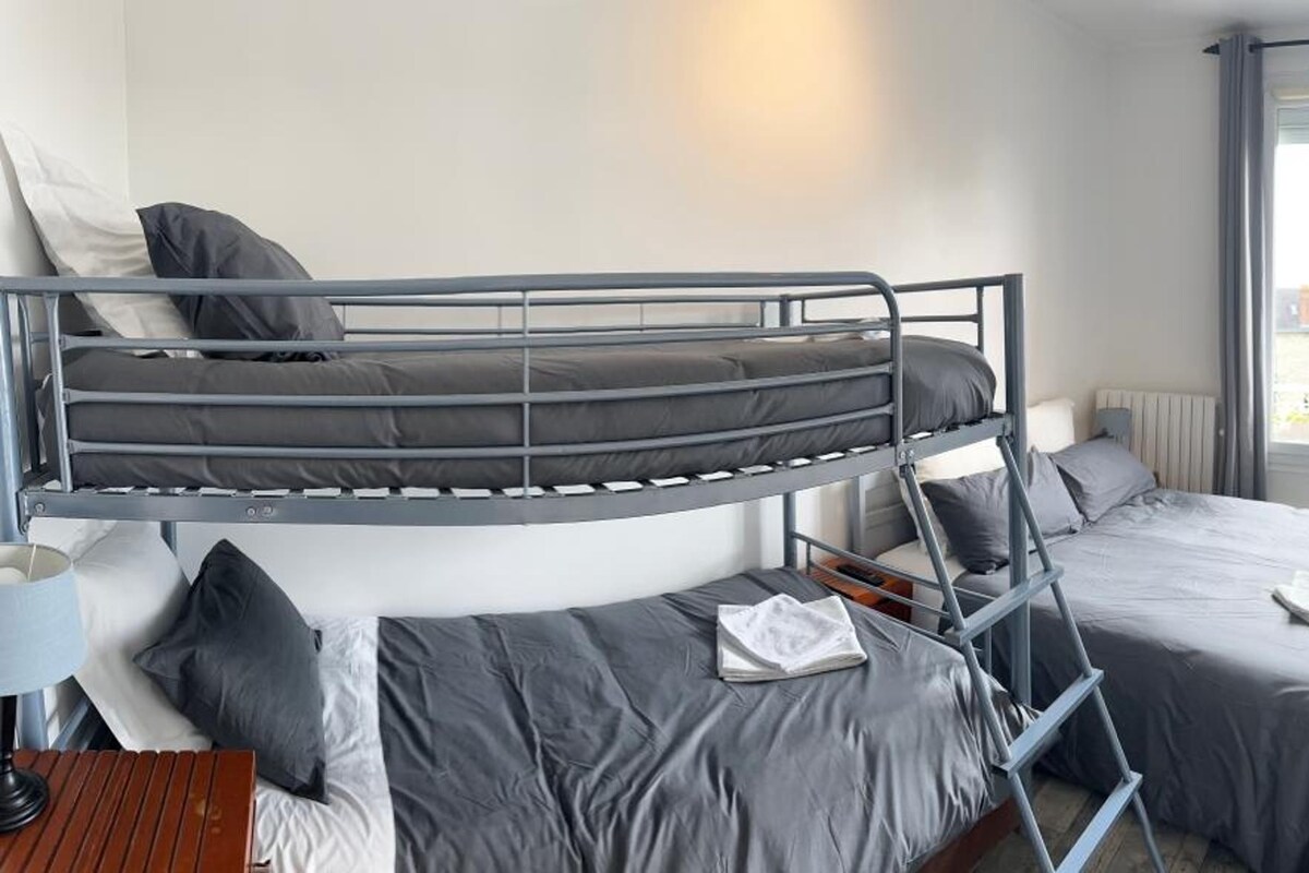 A bunk bed room with a desk, a chair, and a TV mounted on the wall.