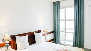 Hotelkamer met een bed, twee bedlampen, een raam met gordijnen en uitzicht op buiten.