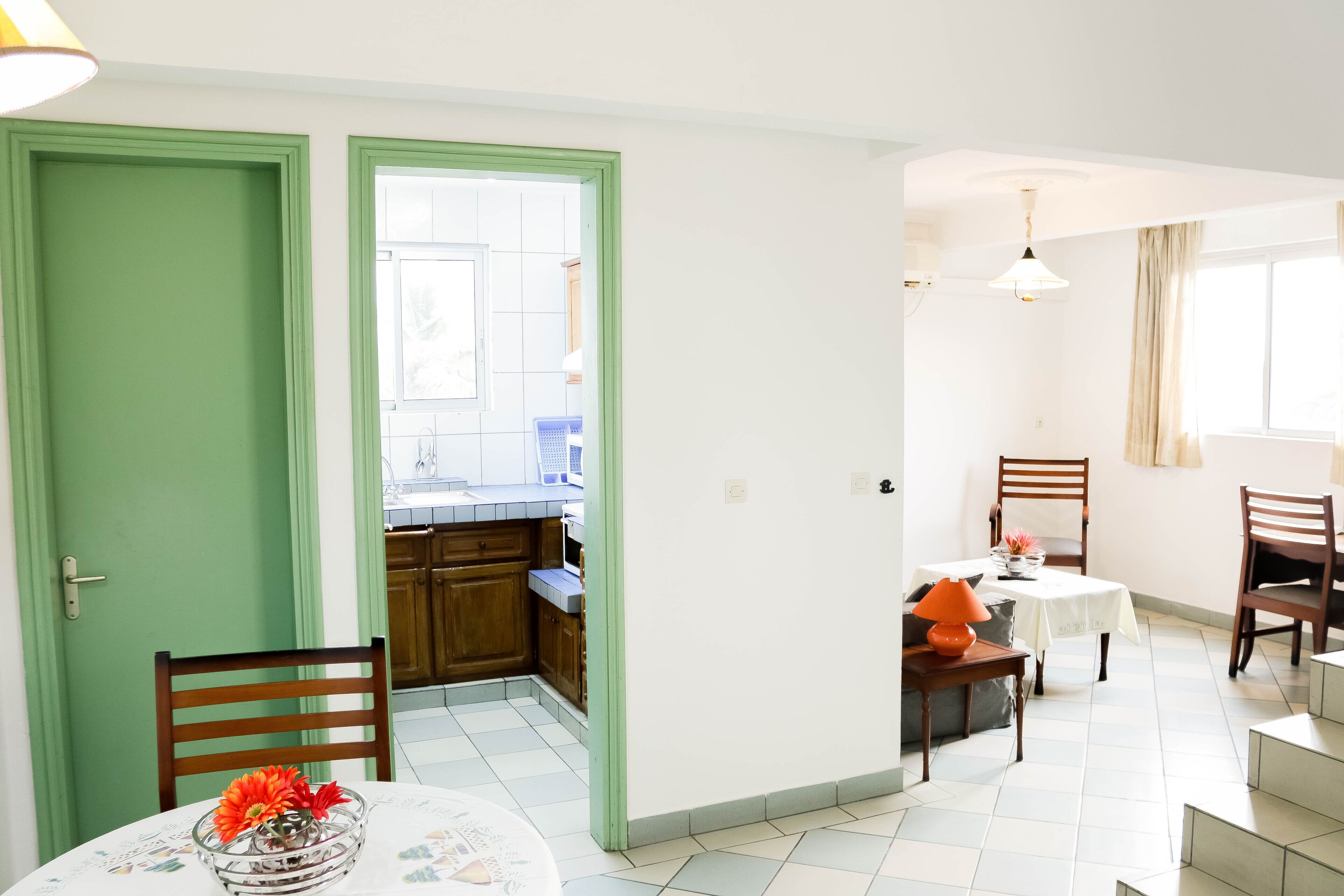 Un coin repas avec une table et des chaises, une cuisine à l’arrière-plan et un escalier menant à un autre niveau.