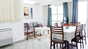 Een eethoek met een tafel voor vier personen, een bank en een televisie op de achtergrond.