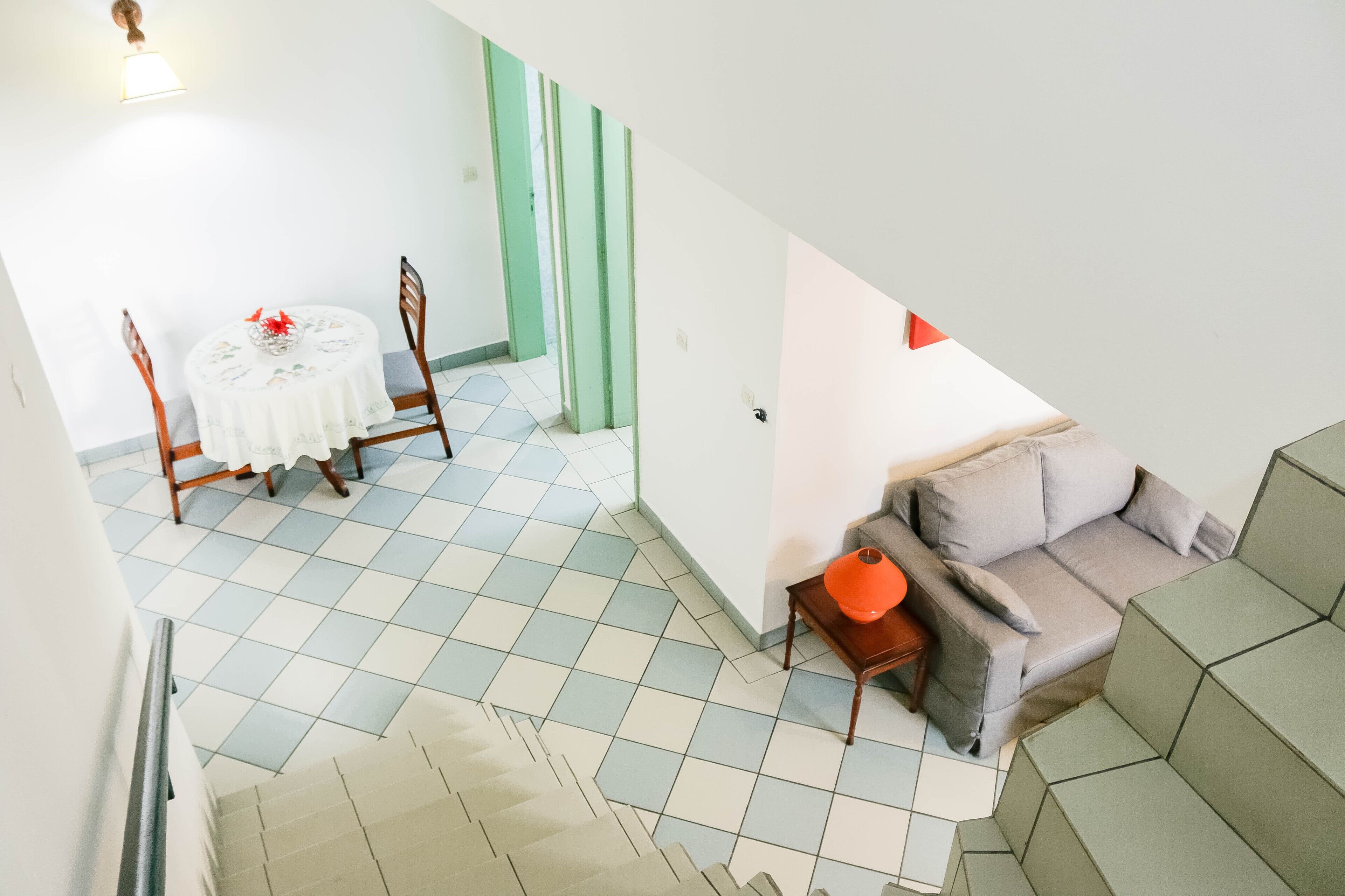 A room with a dining table, chairs, a sofa, and a staircase.