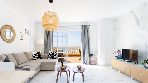 A modern living room with a sofa, two round tables, a TV, and a balcony with curtains. - Casa Ana (Costa Adeje)