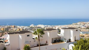 A coastal cityscape with white buildings, a clear blue sky, and the ocean in the background. - Casa Ana (Costa Adeje)