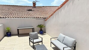 A rooftop terrace with a tiled roof, a white wall, and a seating area with a sofa and chairs. - L'écurie - New house for 5 people, swimming pool (Portiragnes)