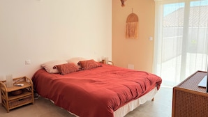 A bedroom with a bed, a wicker side table, a laptop, and a hanging light fixture. - L'écurie - New house for 5 people, swimming pool (Portiragnes)