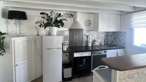 A compact kitchen with white cabinetry, a built-in oven, a sink, and a window providing natural light.