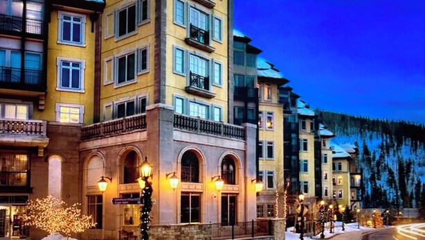 A multi-story hotel with a central courtyard, large windows, and a snow-covered landscape in the background. - Ritz-Carlton Club, Vail, Two Bedroom Residence (Vail)