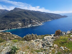 A coastal landscape with rocky terrain and a clear view of the sea.