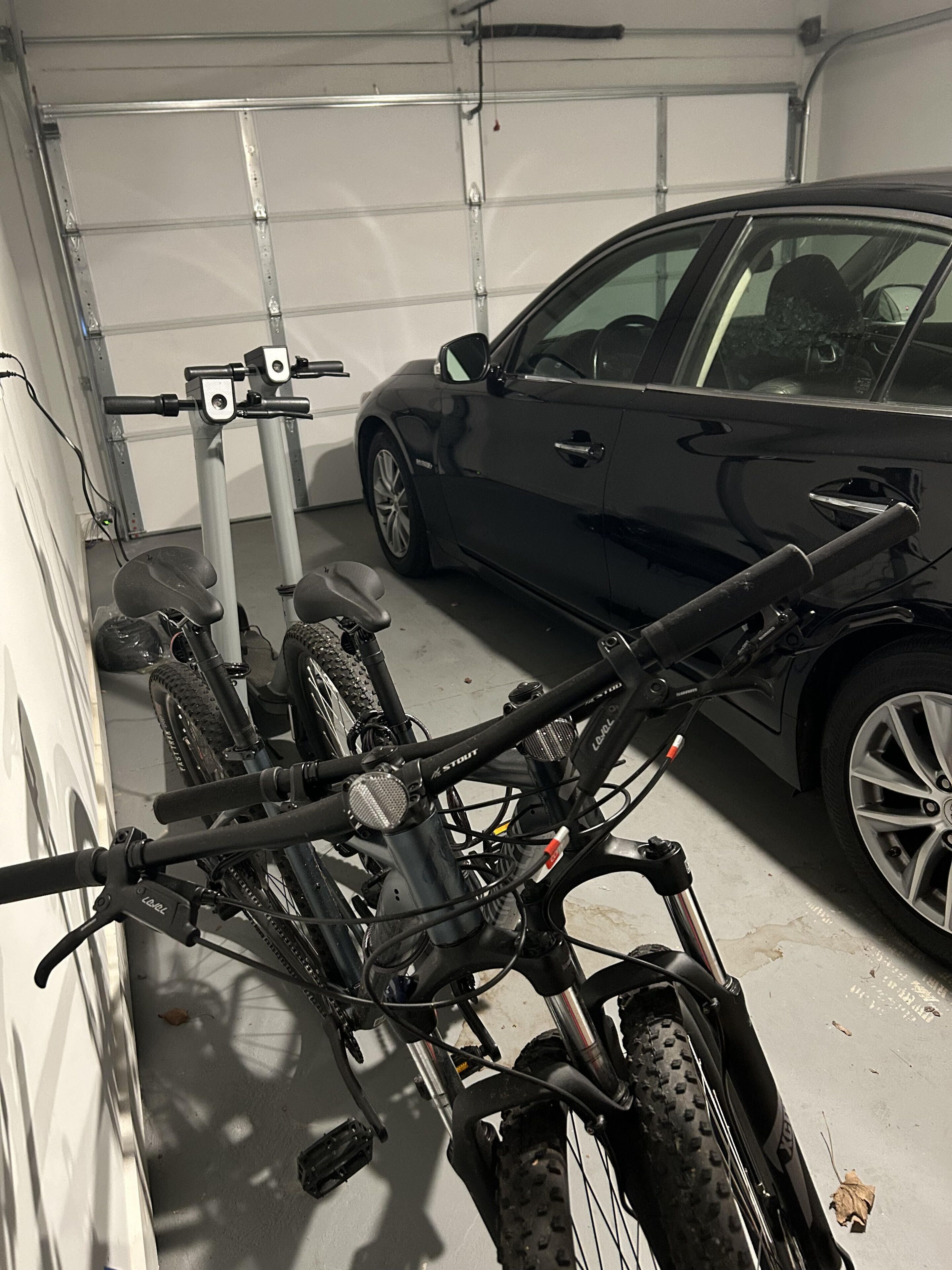 Un garage con rastrelliera per biciclette che contiene due biciclette e un'auto nera parcheggiata all'interno.