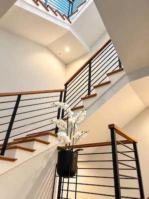 A modern staircase with wooden handrails and black metal balusters, leading to a skylight. - Atlanta Skyline Rooftop, Fire Pit, BeltLine and Garage (Atlanta)