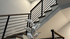 Un escalier moderne avec une lucarne, des murs blancs et une orchidée en pot.