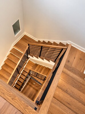 A wooden staircase with a metal railing, leading to an upper floor. - Atlanta Skyline Rooftop, Fire Pit, BeltLine and Garage (Atlanta)