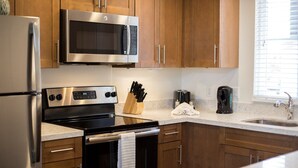 A modern kitchen with stainless steel appliances, wooden cabinets, and a marble countertop.