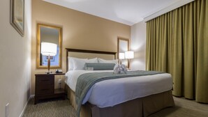 A hotel room with a large bed, bedside lamps, a nightstand, a mirror, and a window with curtains.