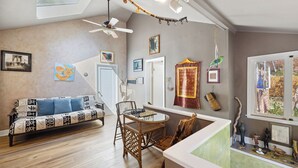 Una sala de estar con un sofá, una mesa con un tablero de ajedrez y una ventana con vistas al exterior.