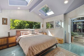 Ein Schlafzimmer mit einem großen Bett, Dachfenstern, Blick ins Grüne und einem Holzschrank.