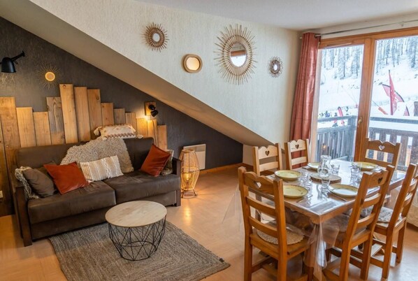 Una sala de estar acogedora con sofá, mesa de centro y mesa de comedor lista para una comida.
