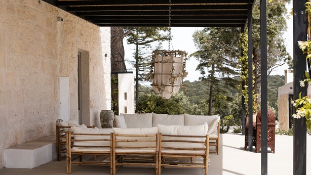Un espacio de estar al aire libre con techo, sofá de bambú y lámpara colgante.