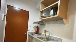 Una cocina compacta con puerta de madera, un lavamanos empotrado y un refrigerador pequeño.