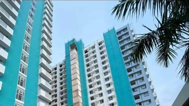 Un edificio de gran altura con piscina y sillones de descanso.
