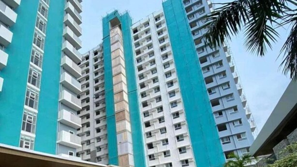 Un edificio alto con piscina y sillones de descanso.