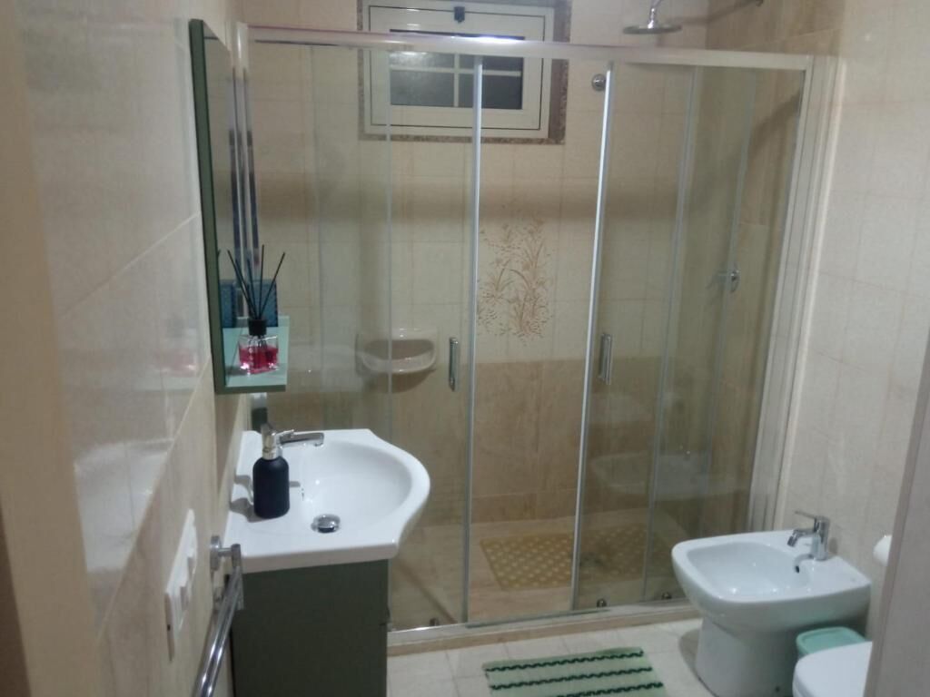 Une salle de bain moderne dotée d’une douche à parois de verre, d’un lavabo et d’un bidet.
