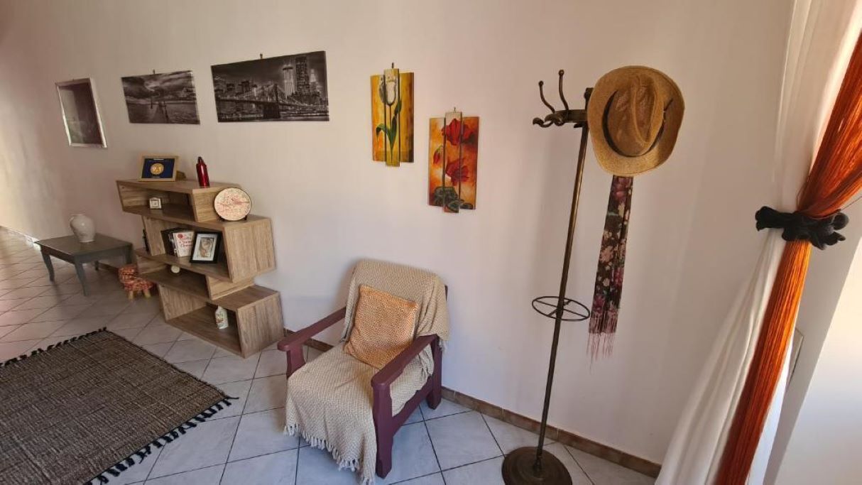 Ein gemütliches Wohnzimmer mit einem Holzstuhl, einer Stehlampe und Wandbildern.