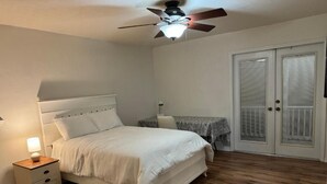 Un dormitorio con cama, mesita de noche y ventilador de techo.