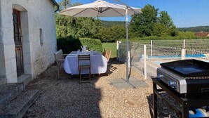 Eine Außenpatio mit einem Esstisch, einem Grill und einem Poolbereich.