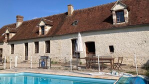 Ein Gebäude mit Schwimmbad, Steinmauern und einem Ziegeldach.