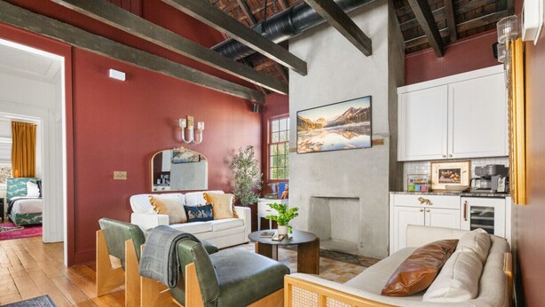 A cozy living room with a fireplace, a dining area, and a kitchen. - Designer Chic 6BR Full Downtown Charleston Duplex (Charleston)