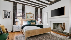 A spacious bedroom with a large bed, a fireplace, and a view of the outdoors. - Designer Chic 6BR Full Downtown Charleston Duplex (Charleston)