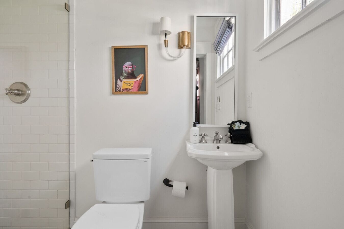 Un baño con inodoro, lavamanos y un cuadro en la pared.