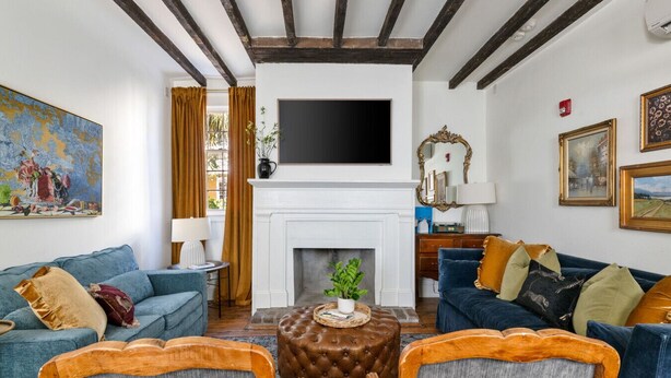 A living room with a fireplace, two sofas, a coffee table, and a TV mounted above the fireplace. - Spacious 3-BR Downtown Stay w/ Patio & Parking (Charleston)