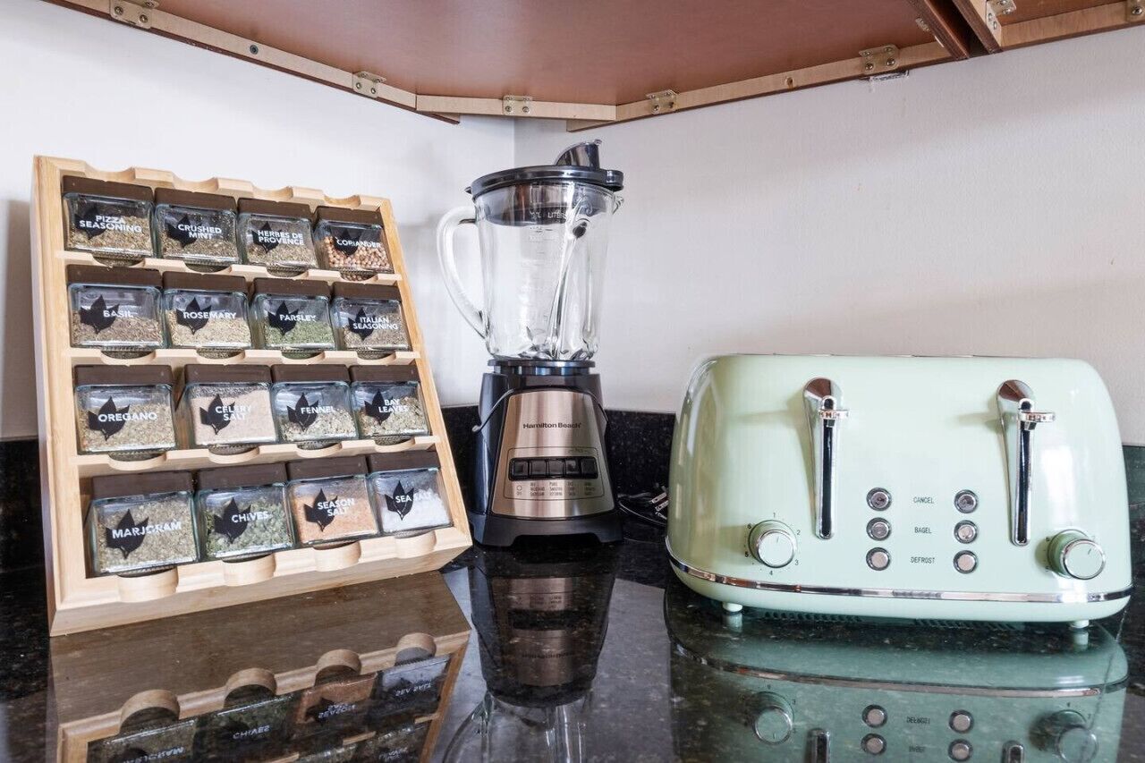 A kitchen with a blender, a toaster, and a spice rack.
