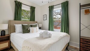 Une chambre à coucher comprenant un lit, une table de chevet, une armoire et un ventilateur de plafond.