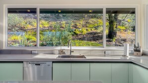 Una cocina moderna con un ventanal grande, electrodomésticos de acero inoxidable y vistas a un jardín.