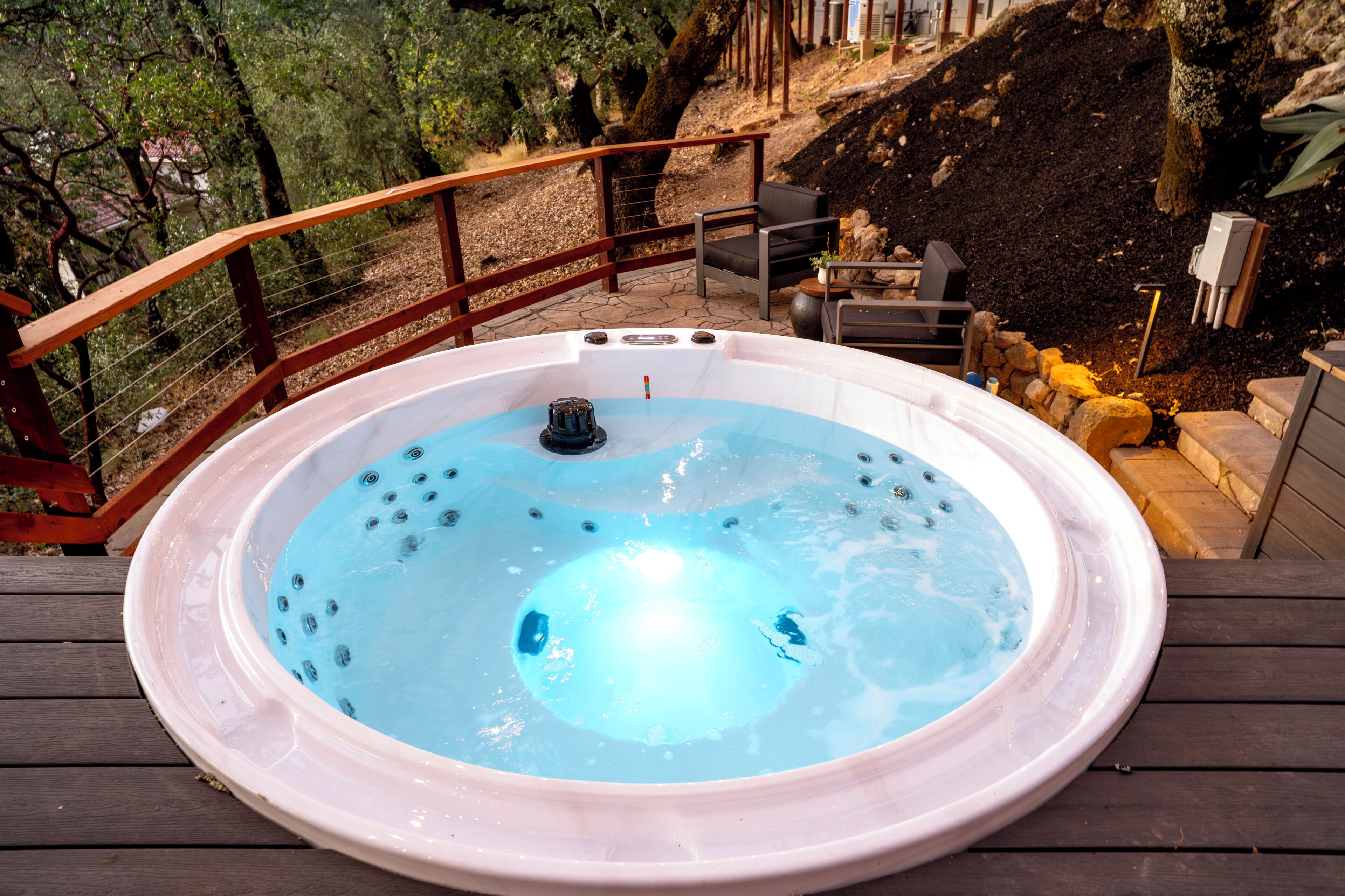 Un jacuzzi en una terraza de madera con barandilla de madera y una silla.