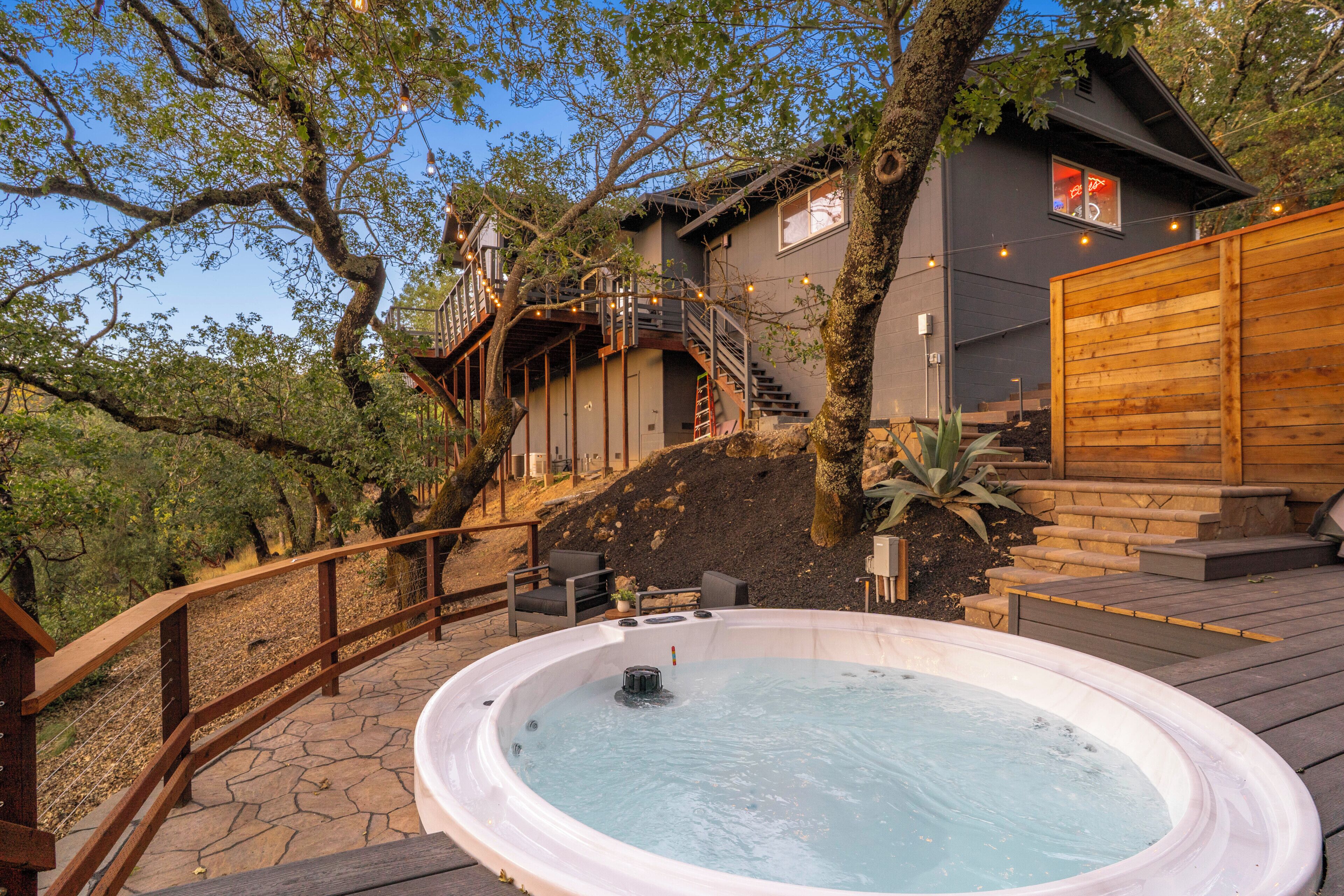 A hot tub on a wooden deck with a staircase leading to a house.