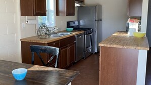 A compact kitchen with wooden cabinets, a stainless steel refrigerator, and a dining area with a table and chairs.