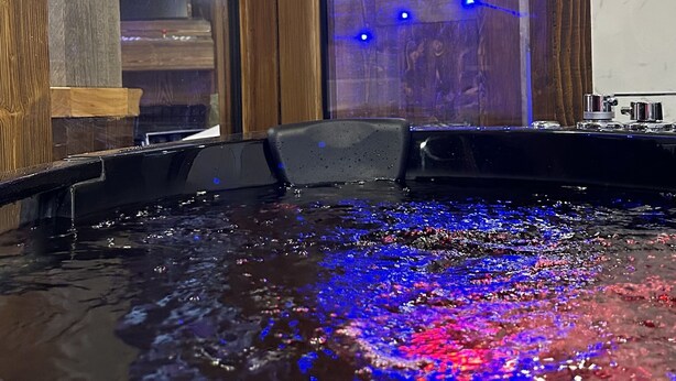 Une pièce dotée d’une grande fenêtre, de poutres en bois et d’un élément décoratif aquatique illuminé de lumière bleue.