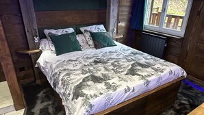 Une chambre à coucher avec un lit en bois, un banc et une fenêtre donnant sur l’extérieur.