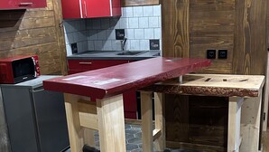 Une cuisine avec une table en bois, des placards rouges et un mur recouvert de carreaux.